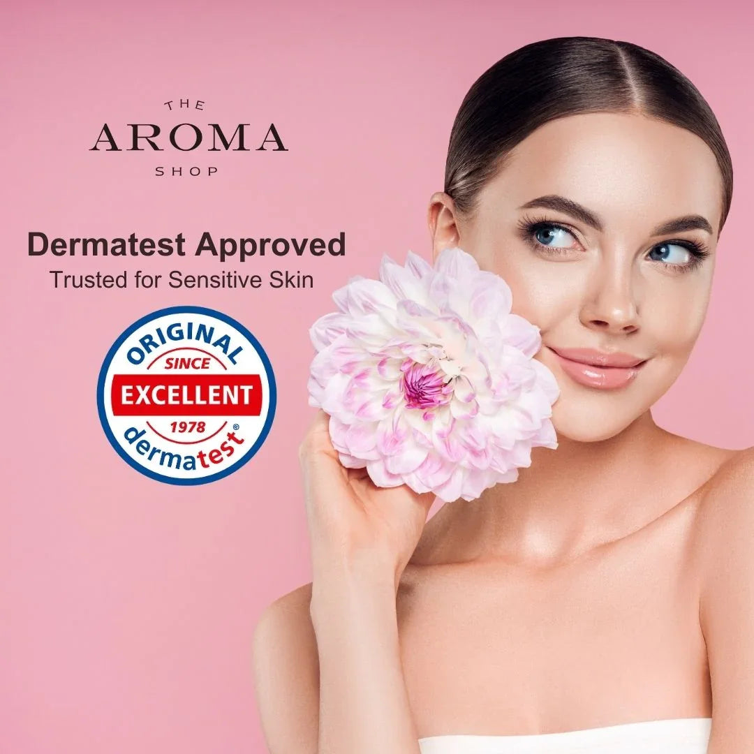 Woman holding a pink flower with 'The Aroma Shop' branding and Dermatest approval on a pink background.