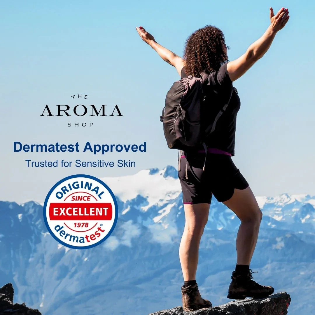 Person with arms outstretched on a mountain top, Aroma Shop branding and Dermatest approval logo.